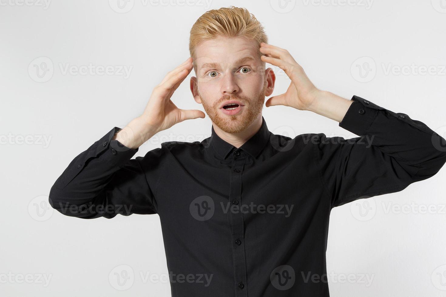 Shock excited Redheaded young man with red beard with wow emotions. Guy in black shirt isolated. Emotional male face close up. People Person Portrait with surprised expressions. Copy space photo
