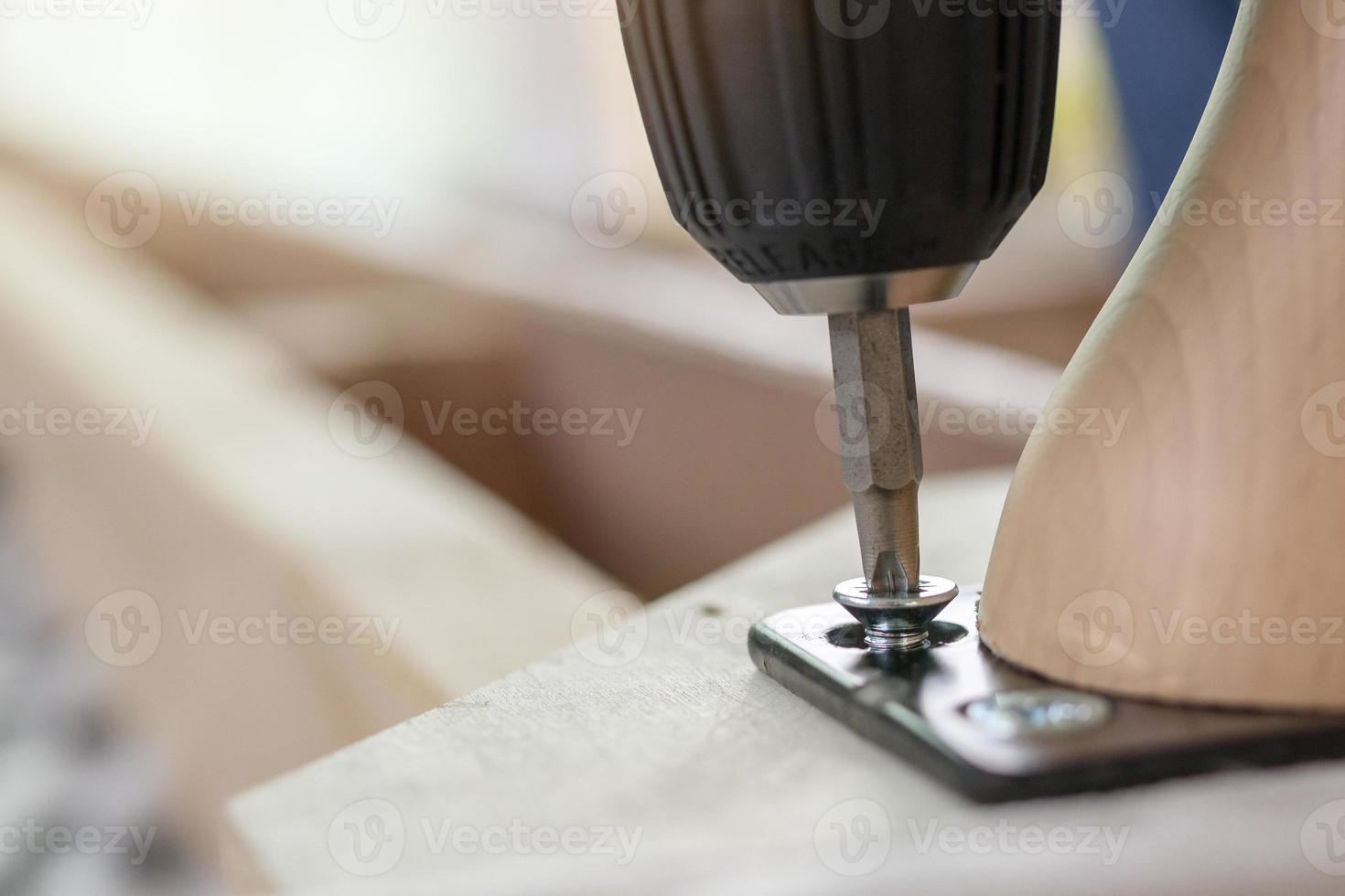 man assembling sofa furniture at home using cordless screwdriver photo