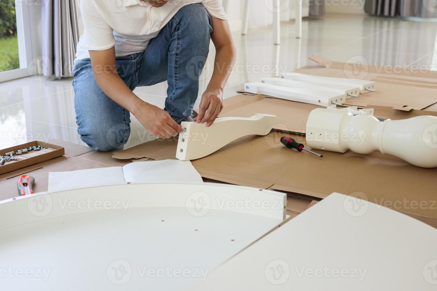 hombre montando muebles de mesa blancos en casa foto