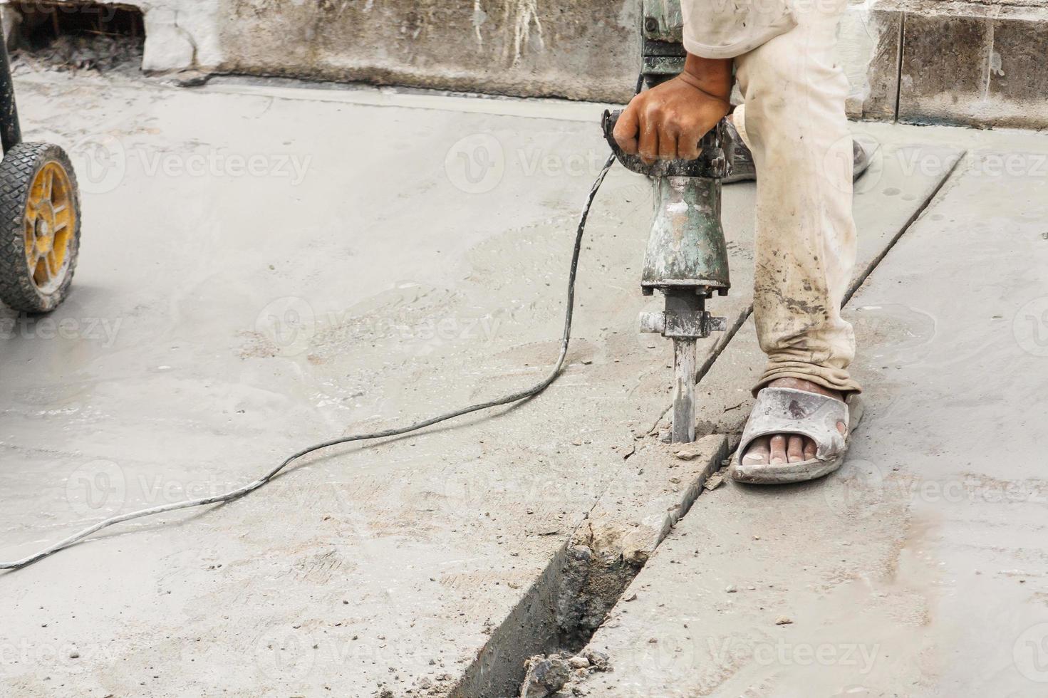 Construction worker using jackhammer drilling concrete surface photo