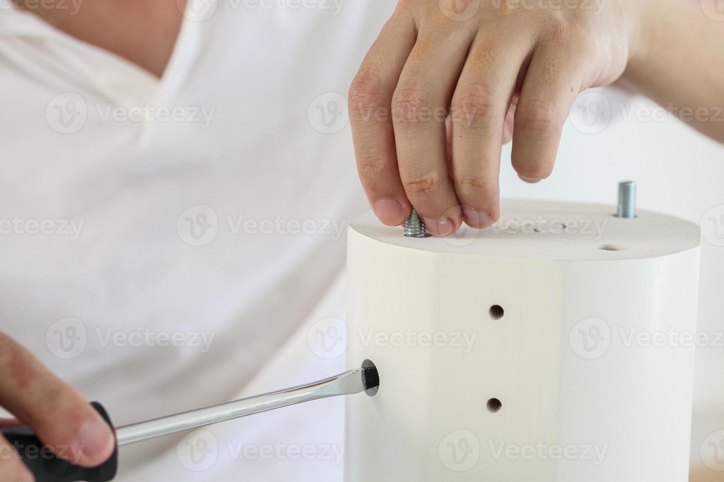 Asian man assembling white table furniture at home photo