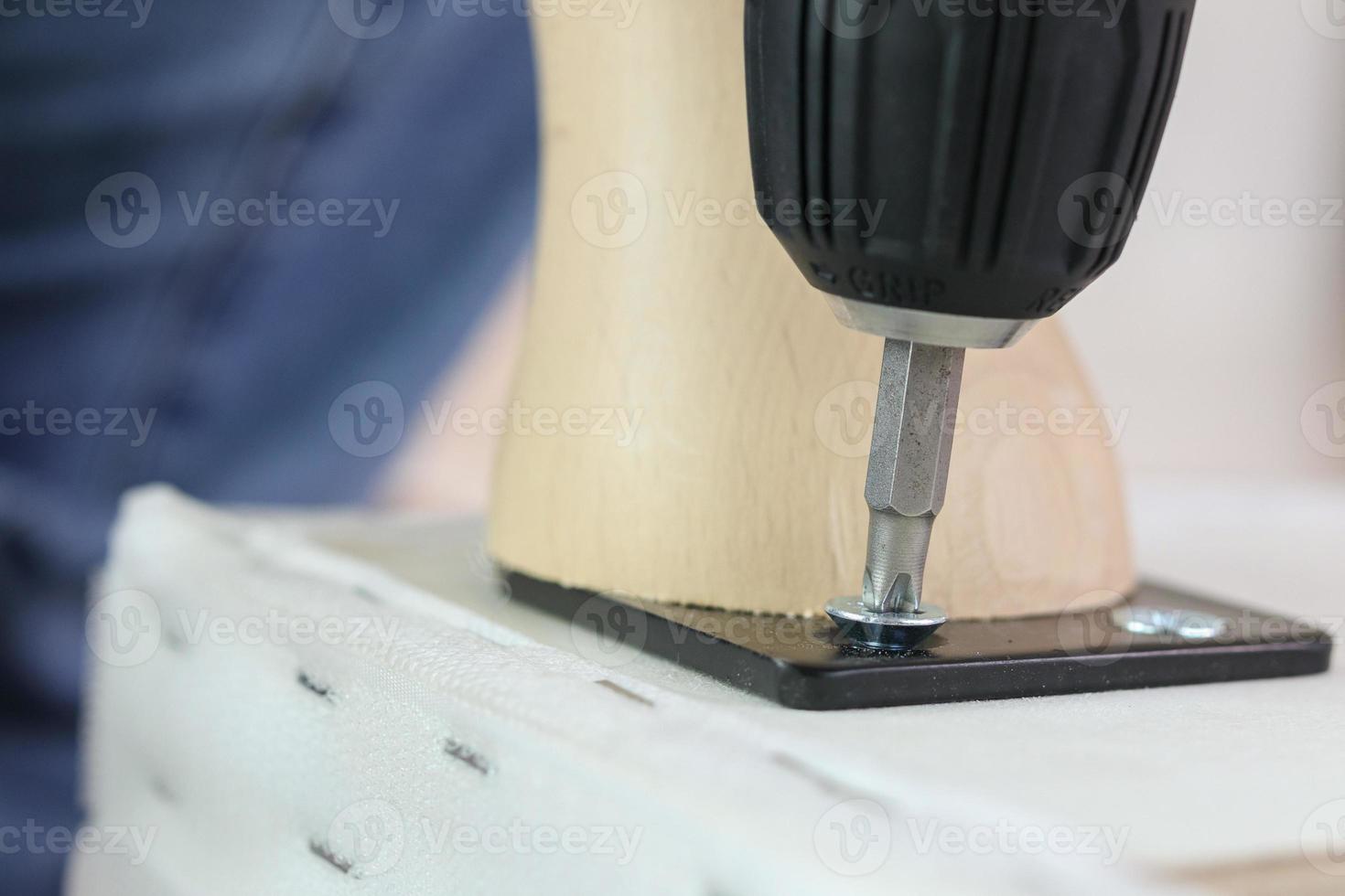 man assembling sofa furniture at home using cordless screwdriver photo