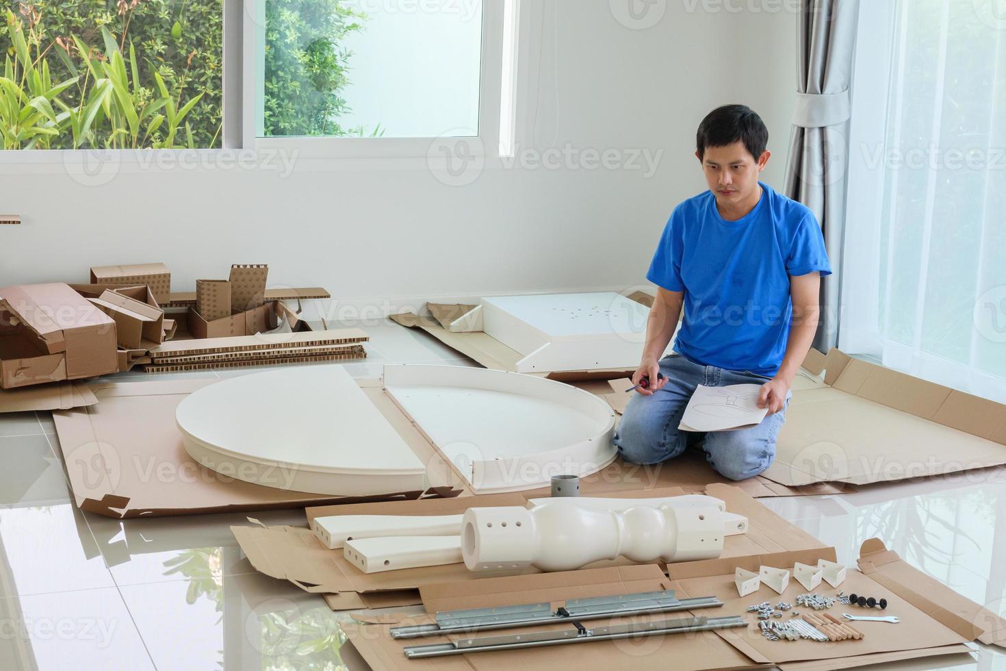 Man assembling white round table furniture at home photo