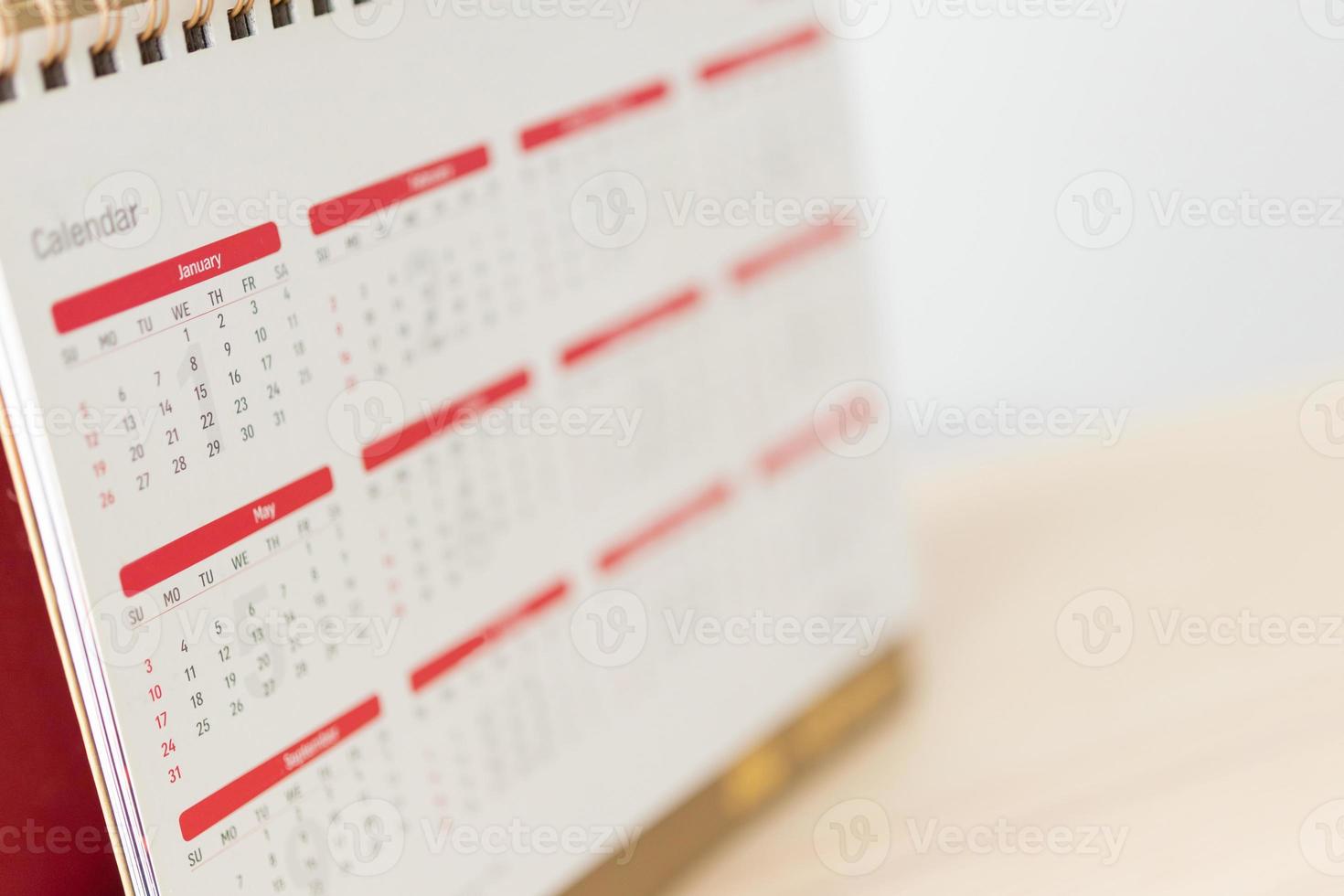 página del calendario de cerca en la mesa de madera con fondo de pared blanca concepto de reunión de cita de planificación empresarial foto