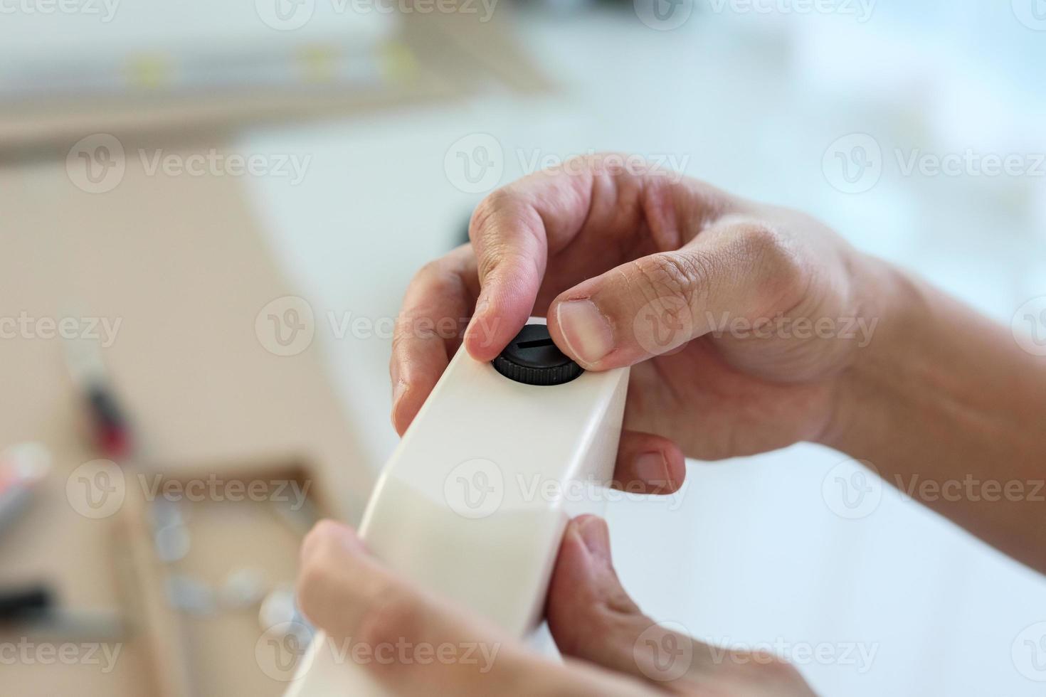 Asian man assembling furniture at home with adjustable table leg photo