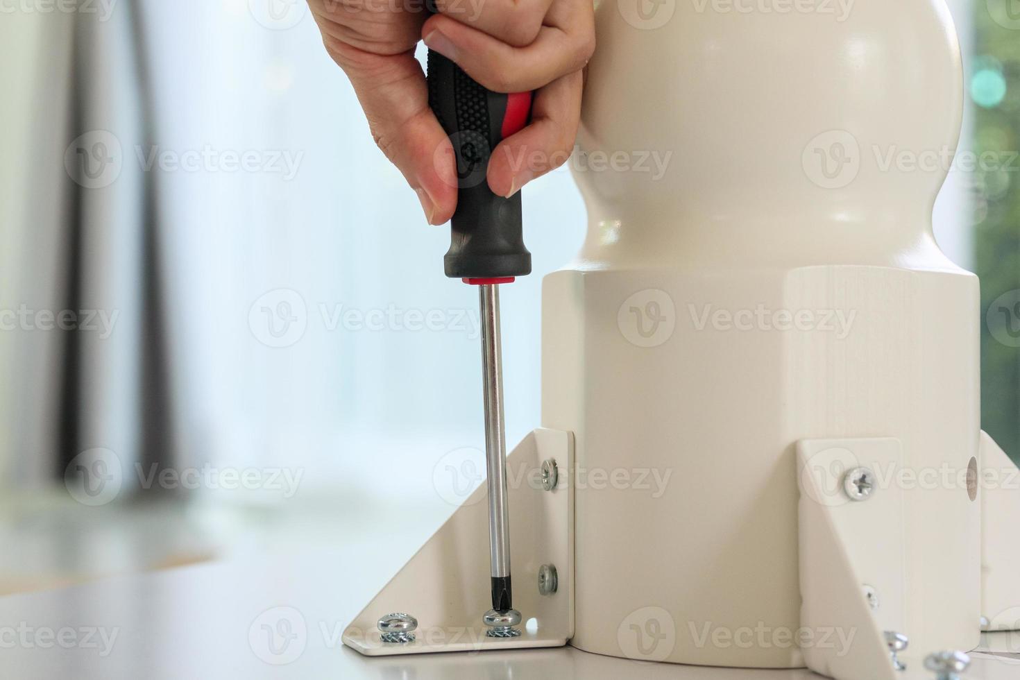 Asian man assembling white table furniture at home photo