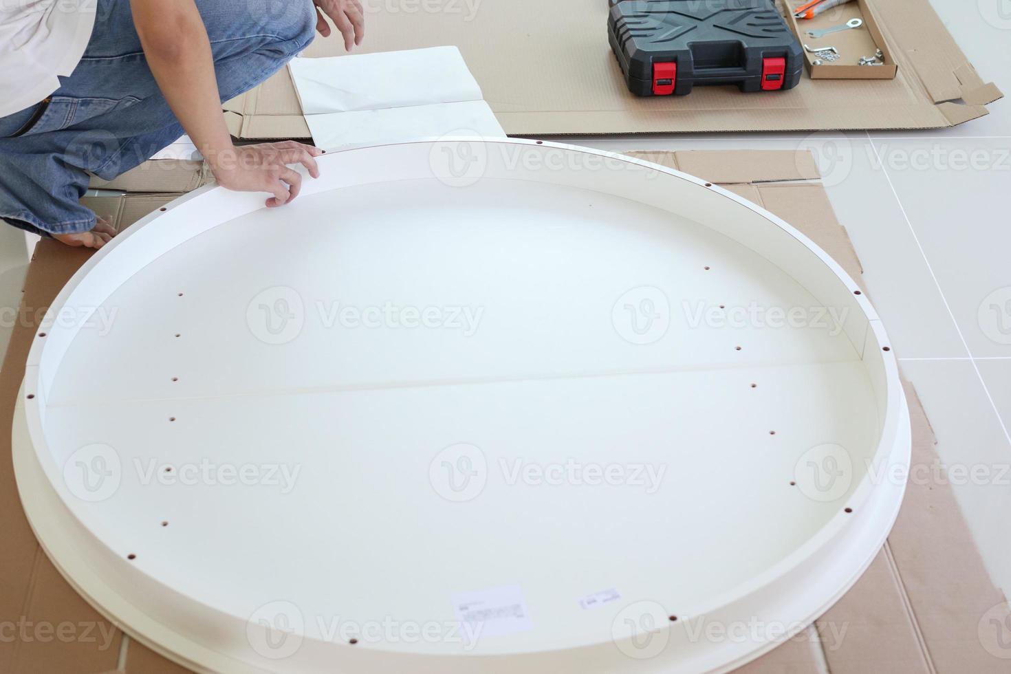 Asian man assembling white table furniture at home photo