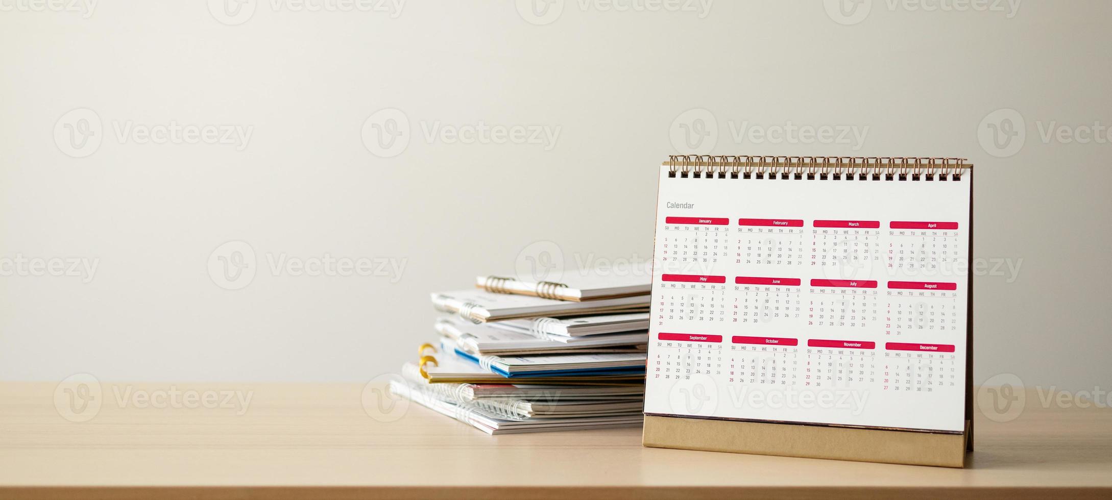 Calendar page close up on wood table with white wall background business planning appointment meeting concept photo