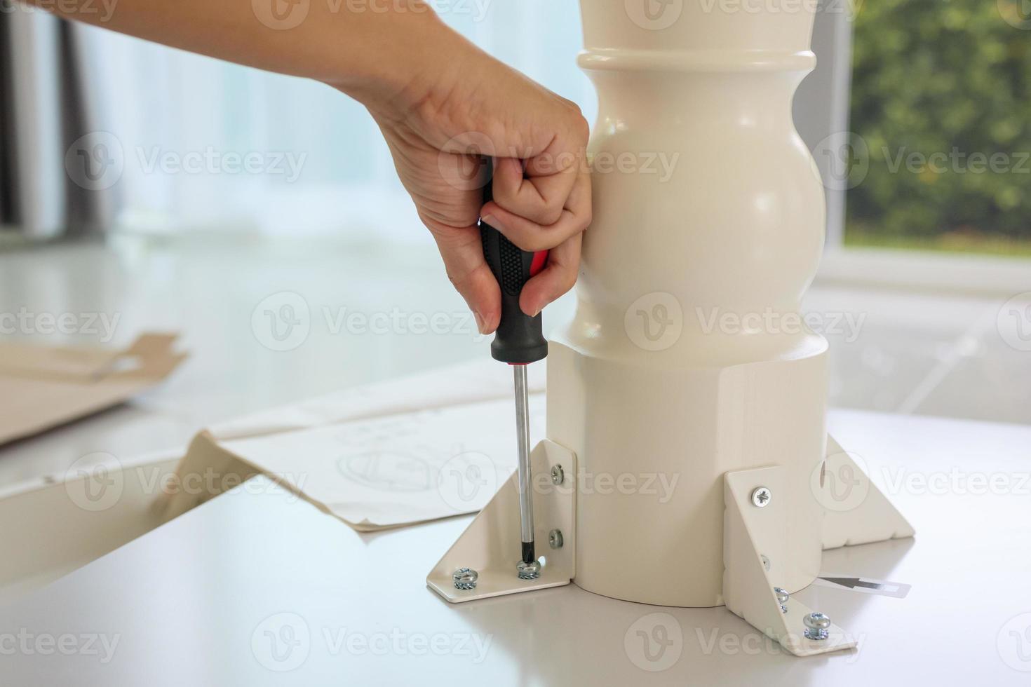 Asian man assembling white table furniture at home photo
