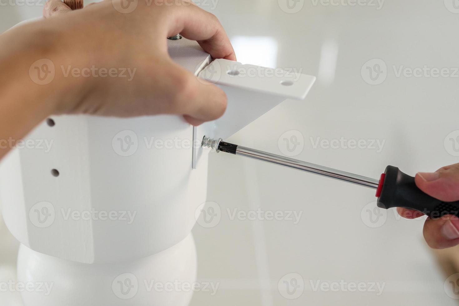 Asian man assembling white table furniture at home photo