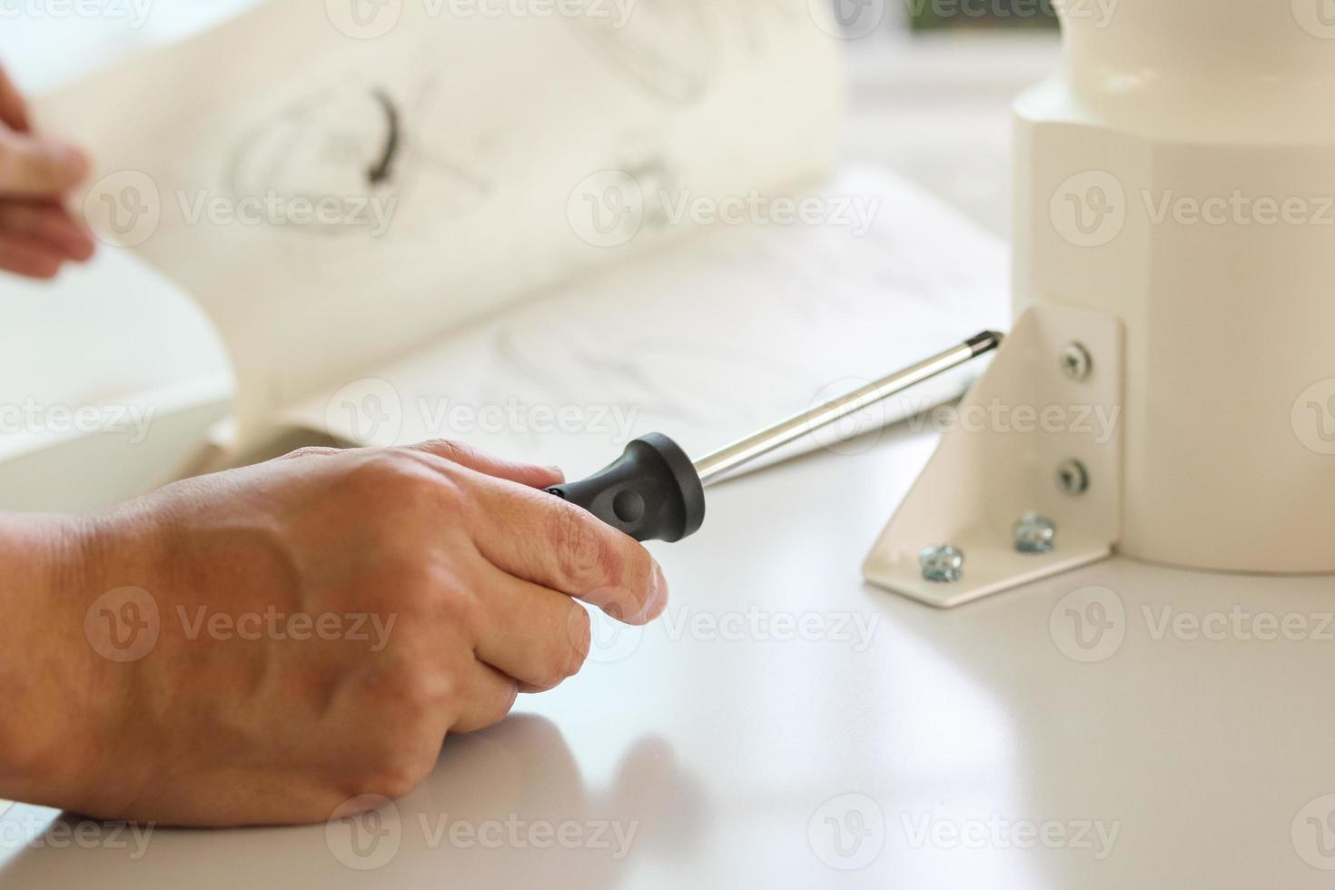 Asian man assembling white table furniture at home photo