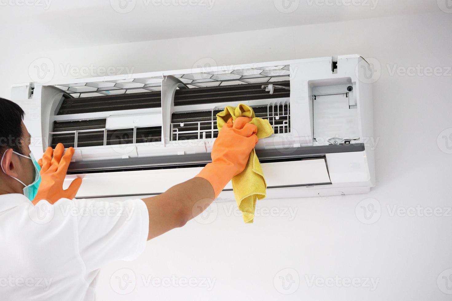 Asian man cleaning air conditioner with microfiber cloth photo