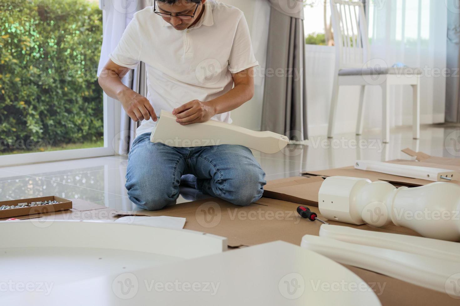 Man assembling white table furniture at home photo