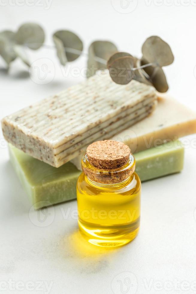 Natural soap bars with herbal ingredients. Handmade product, organic cosmetic on white. Euclyptus branch and essential oil in a glass bottle photo