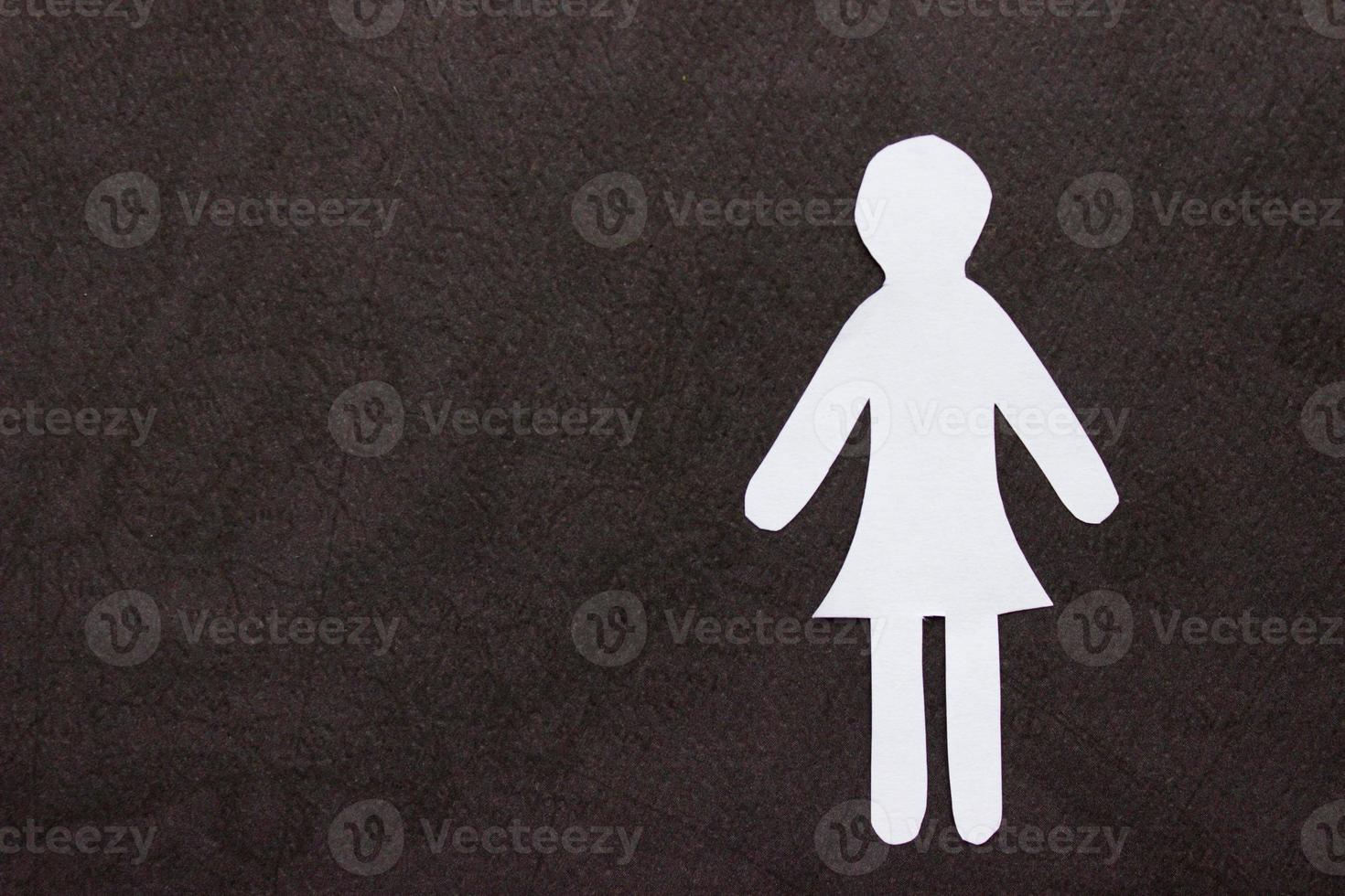 Silhouette of a woman in dress of white paper, cut by hand. On right side of the photo on black background. With copy space