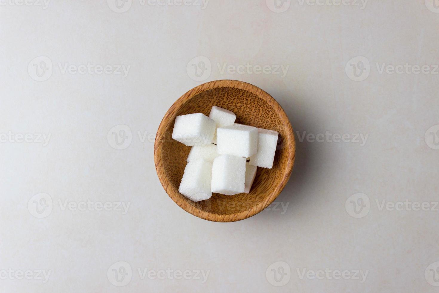 cubos de azúcar en platos de madera en el centro de la mesa de la cocina. vista superior foto