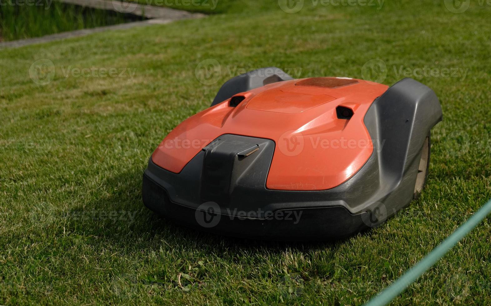 Robotic Lawn Mower on green grass background.Automatic robot lawnmower in modern garden.Green grass trimming with lawn mower. Close-up view of the lawn mower dirty blade after mowing the lawn. photo