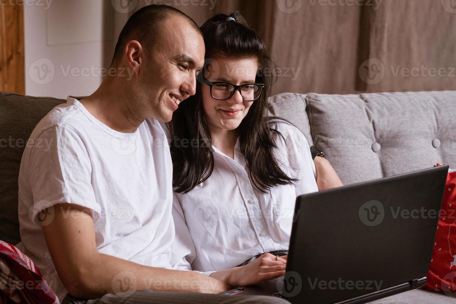 A married couple sitting at home on the sofa with a laptop order goods online photo