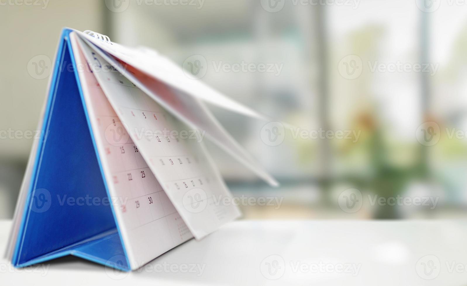 white paper desk calendar on wood table with blurred bokeh background appointment and business meeting concept photo