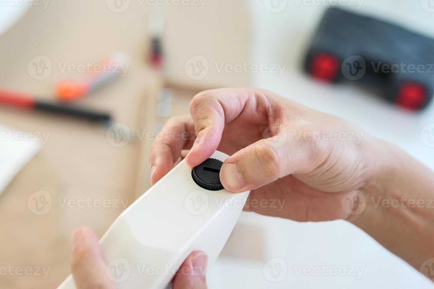 Asian man assembling furniture at home with adjustable table leg photo