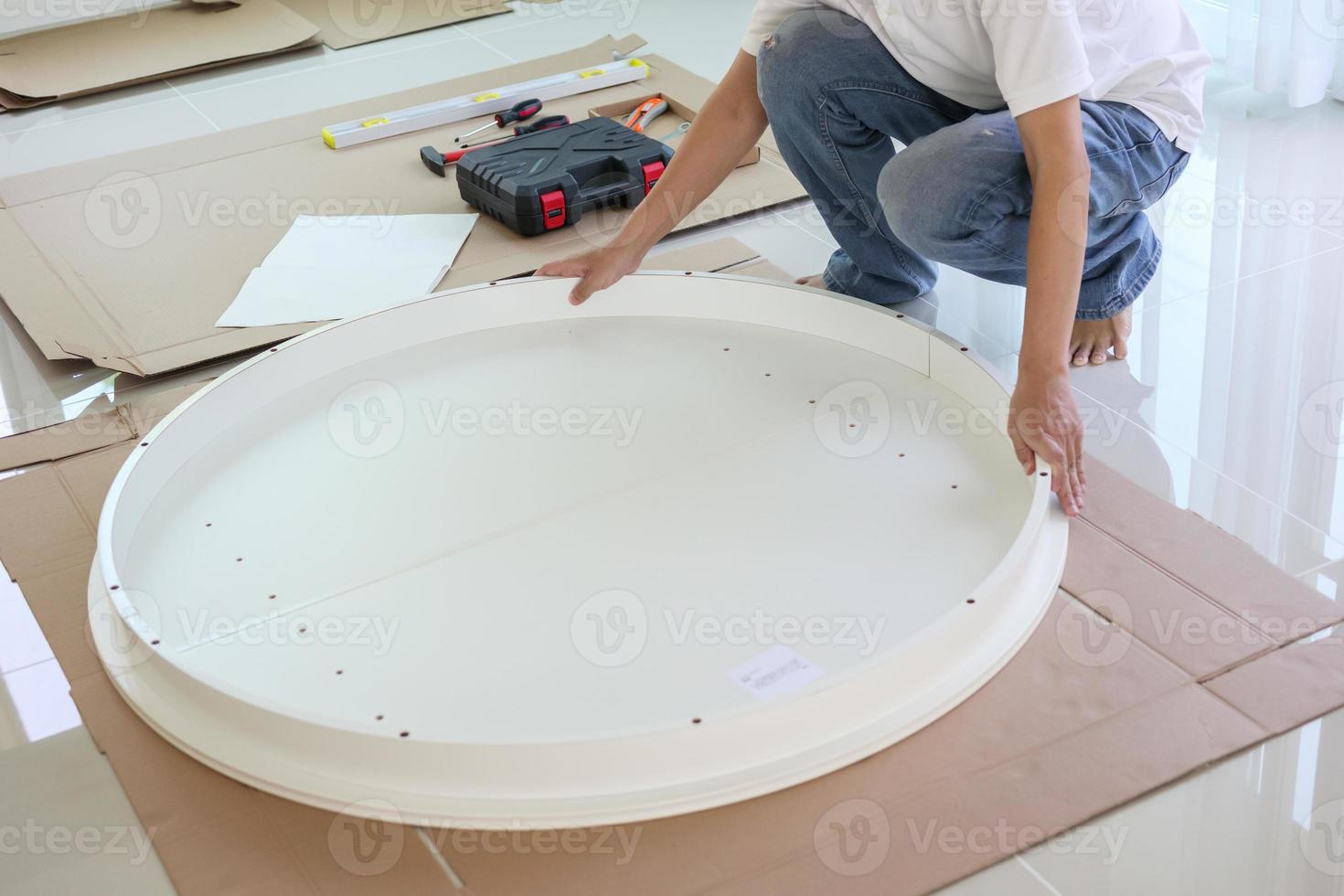Asian man assembling white table furniture at home photo