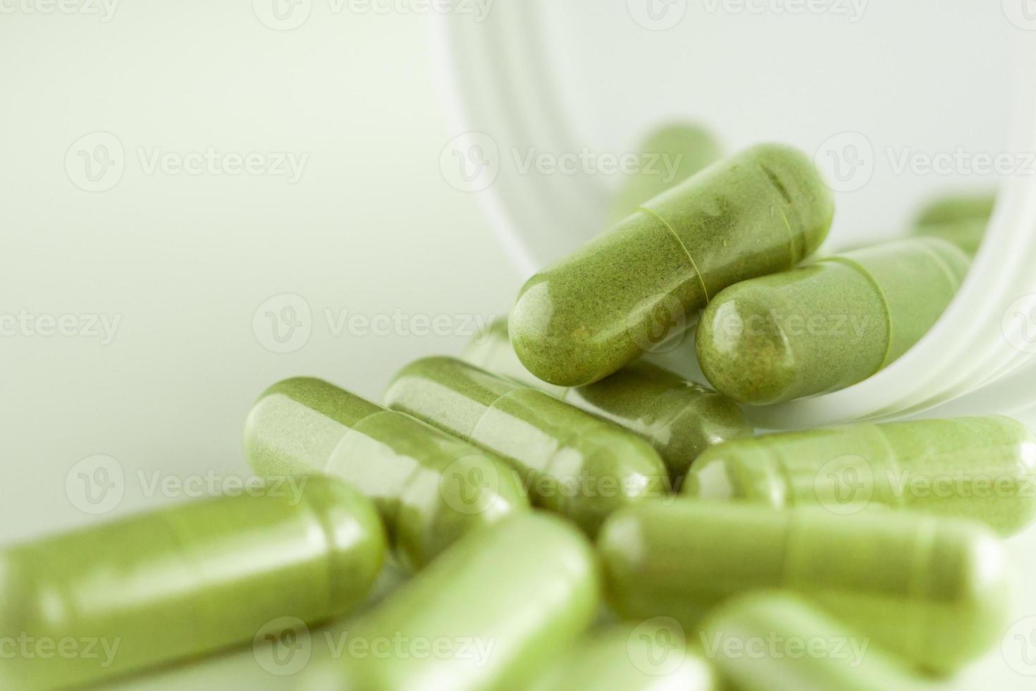 Herbal medicine capsules with bottle on white background photo