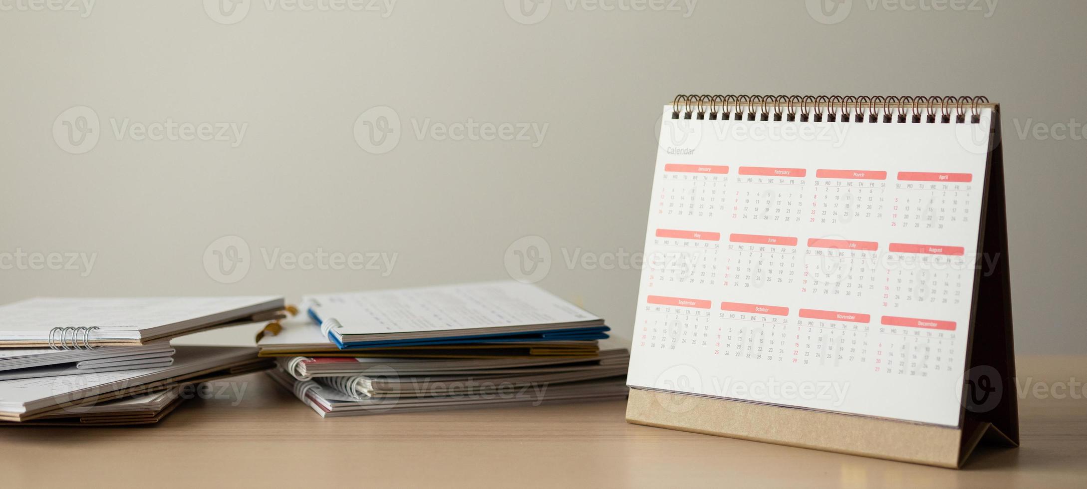 Calendar page close up on wood table with white wall background business planning appointment meeting concept photo