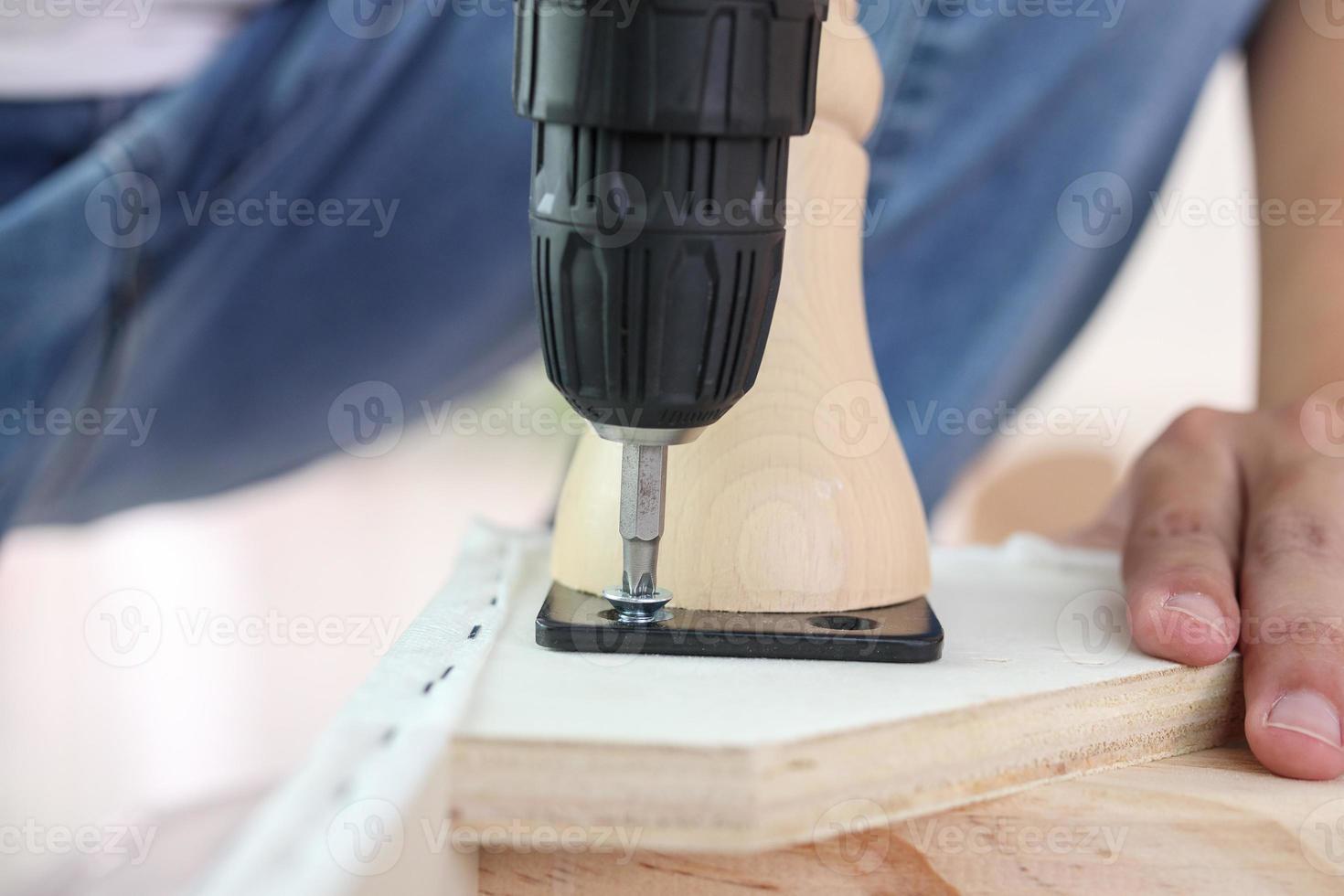 man assembling sofa furniture at home using cordless screwdriver photo