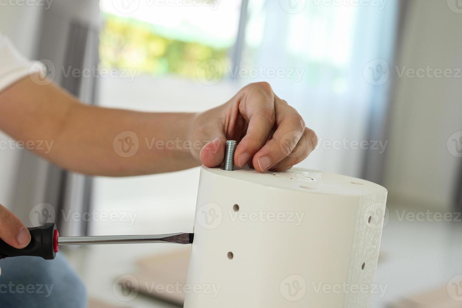 Asian man assembling white table furniture at home photo