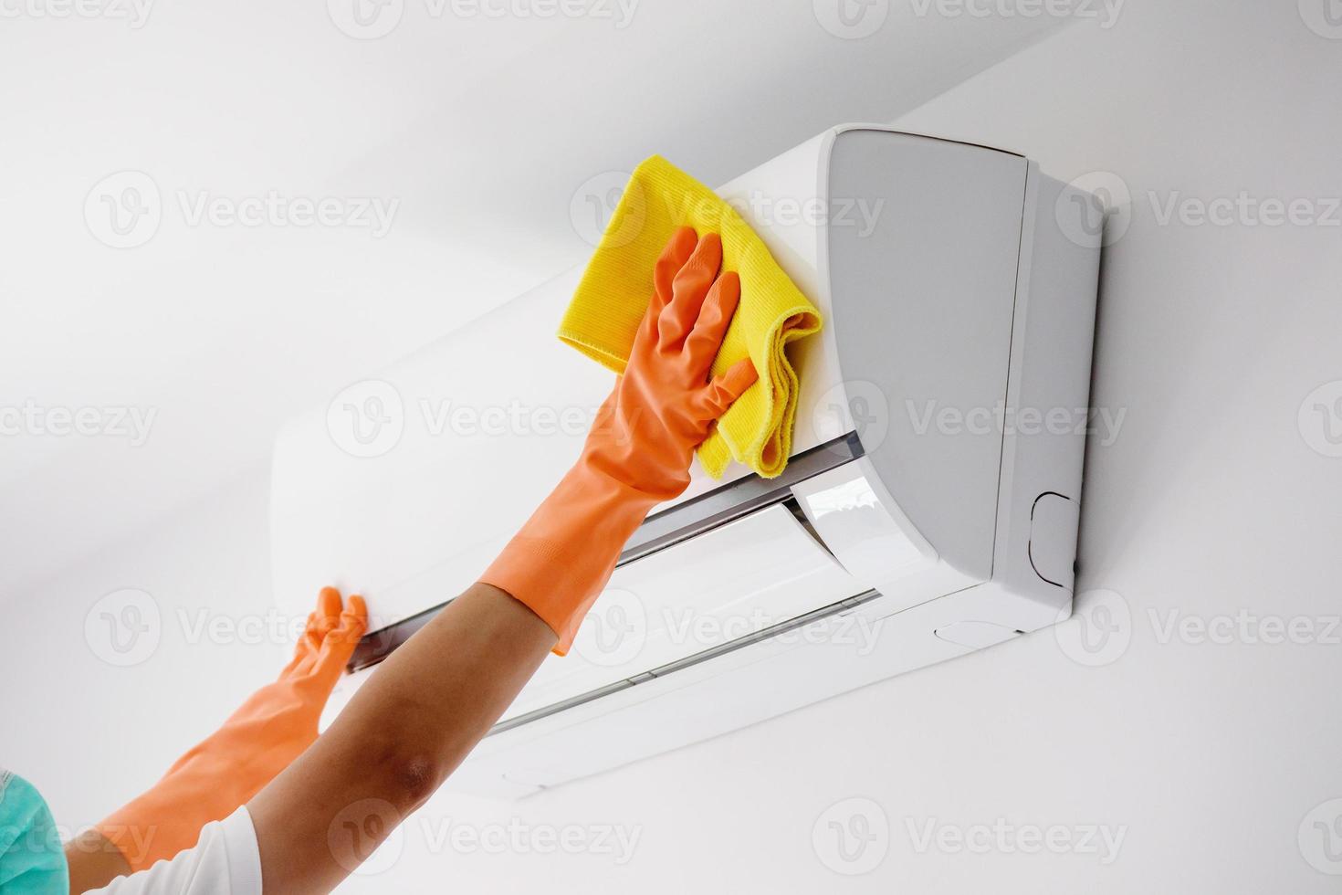 Asian man cleaning air conditioner with microfiber cloth photo