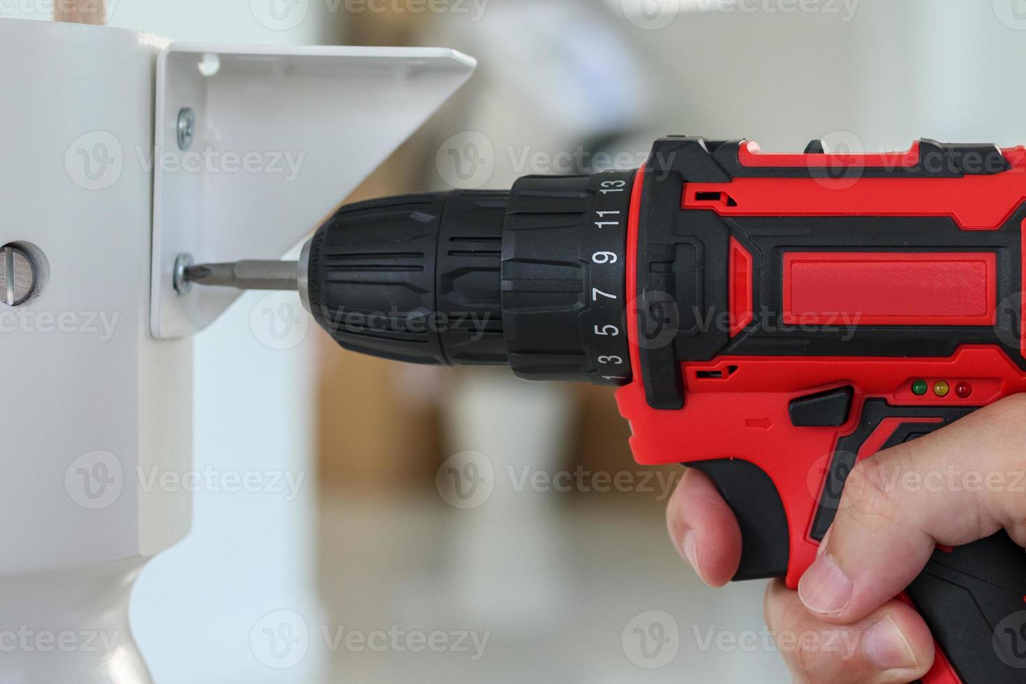 man assembling white table furniture at home using cordless screwdriver photo