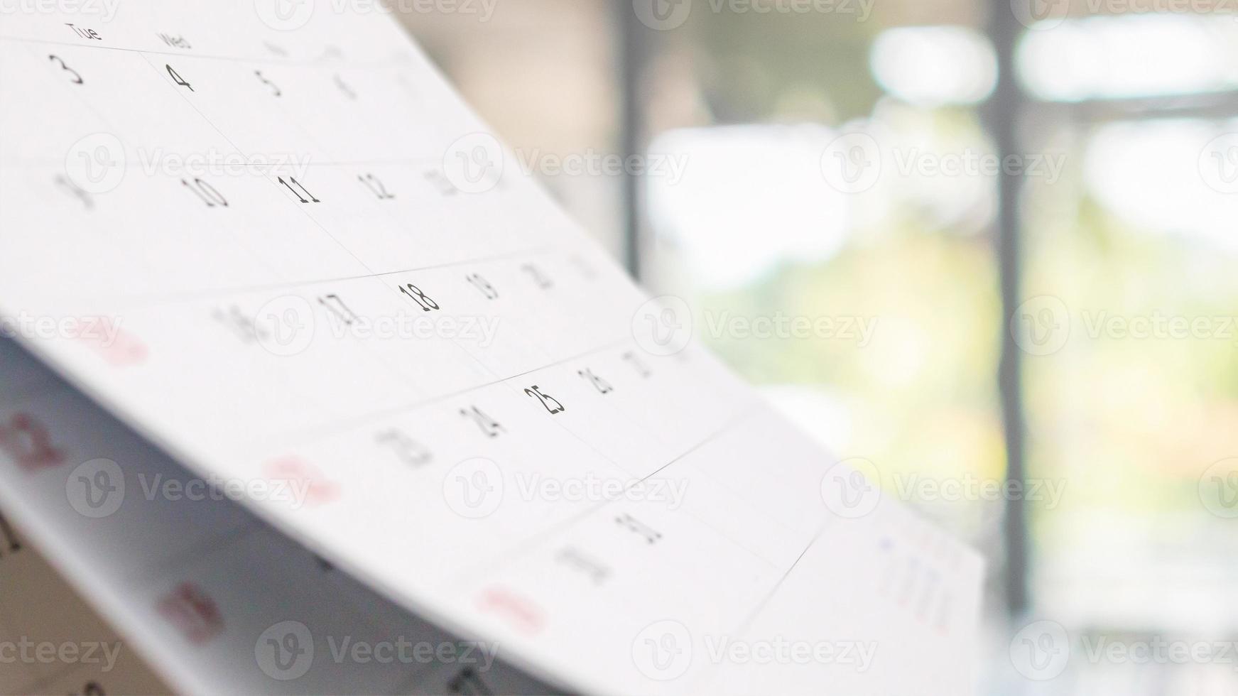 Close up white paper desk calendar with blurred bokeh background appointment and business meeting concept photo