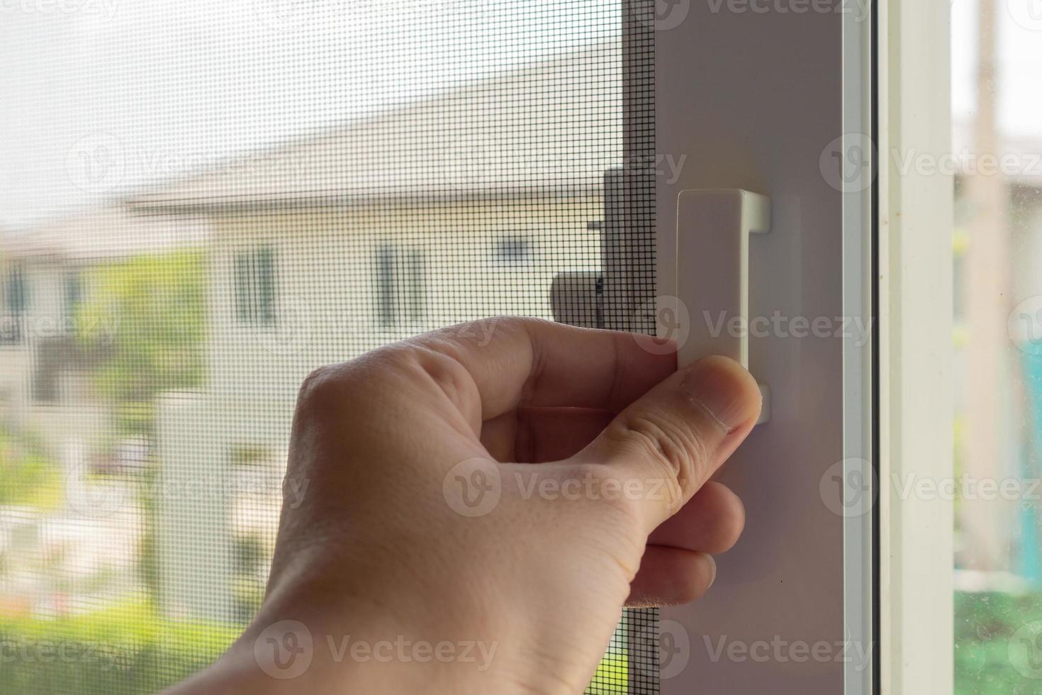 Hand hold mosquito net wire screen handle on house window photo