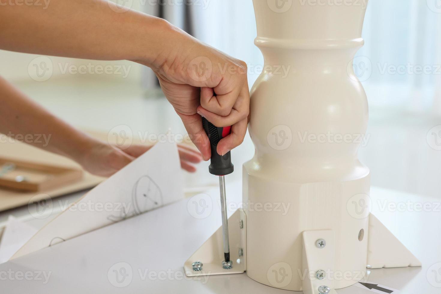 Asian man assembling white table furniture at home photo