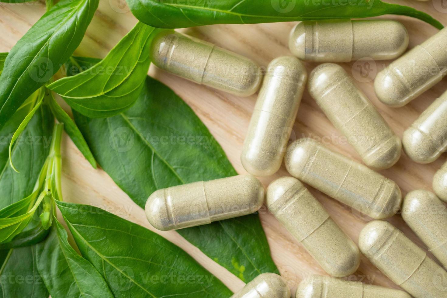 Herbal medicine capsules with Andrographis paniculata leaf on wood table photo