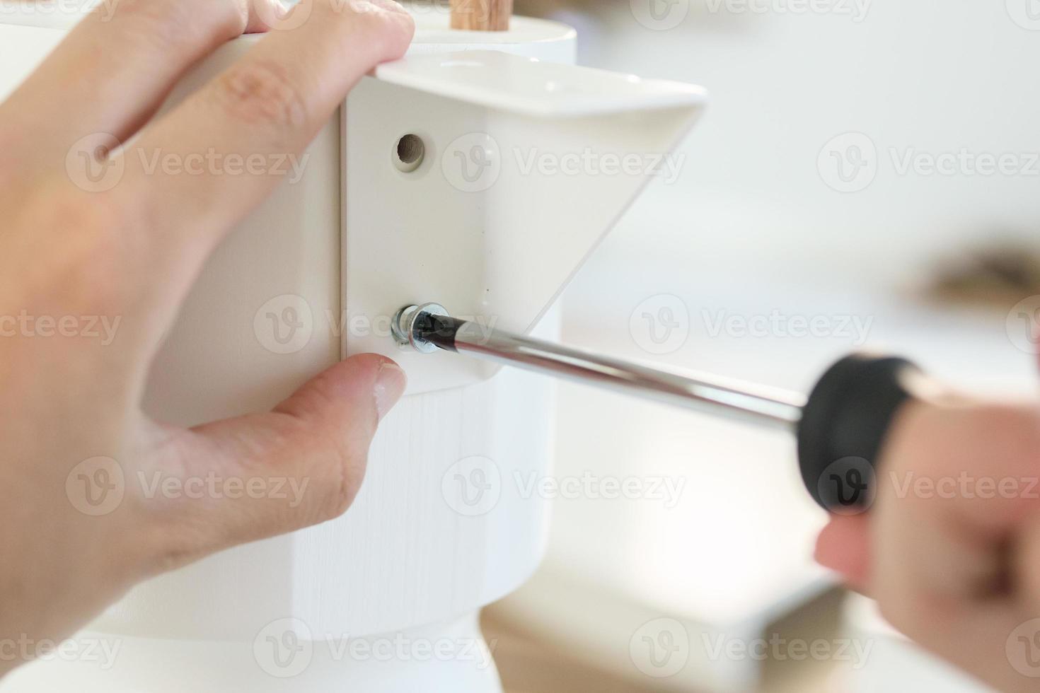 Asian man assembling white table furniture at home photo