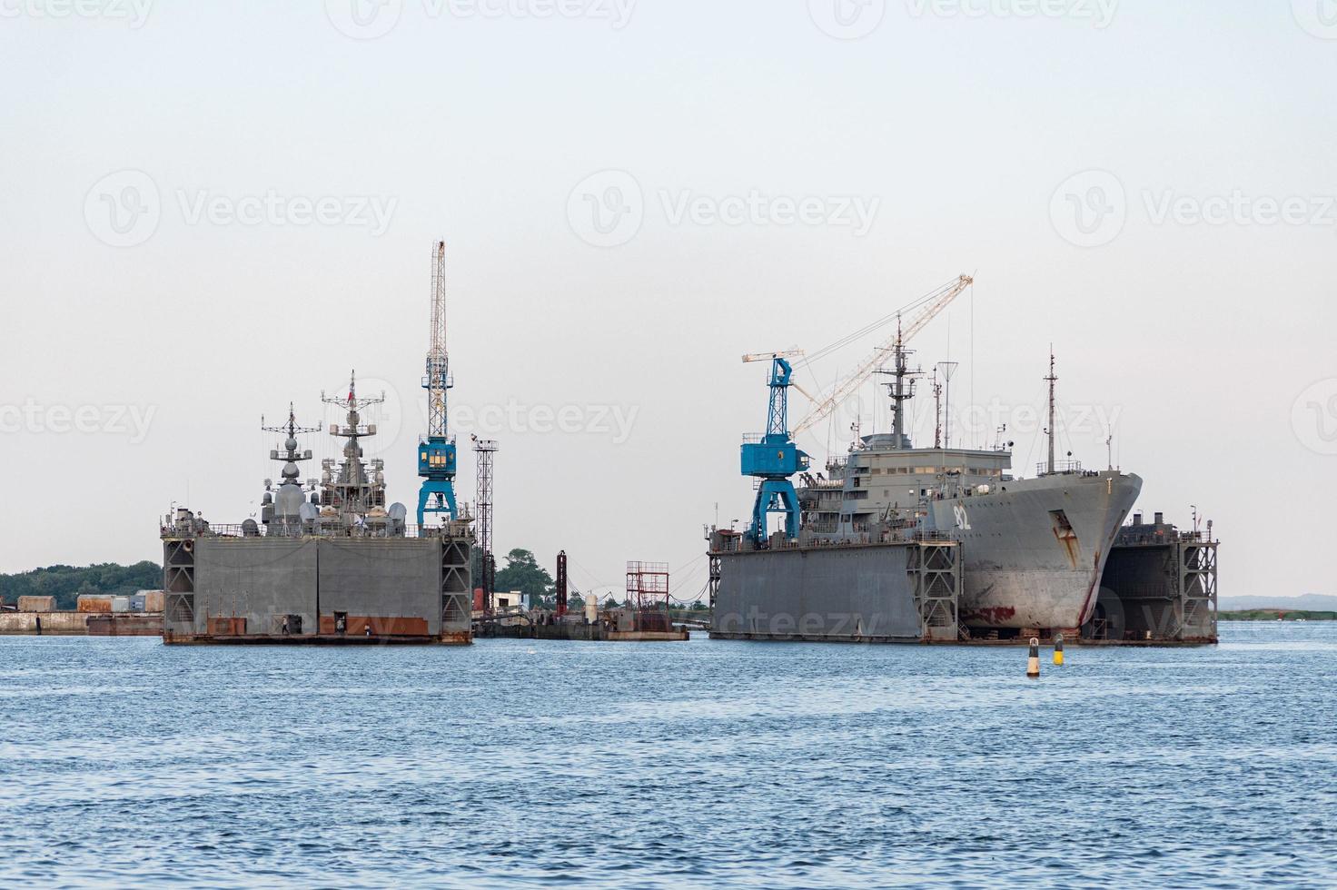 grandes barcos de la armada de hierro en el astillero para su reparación. gran grúa en el astillero. puerto de mar azul foto