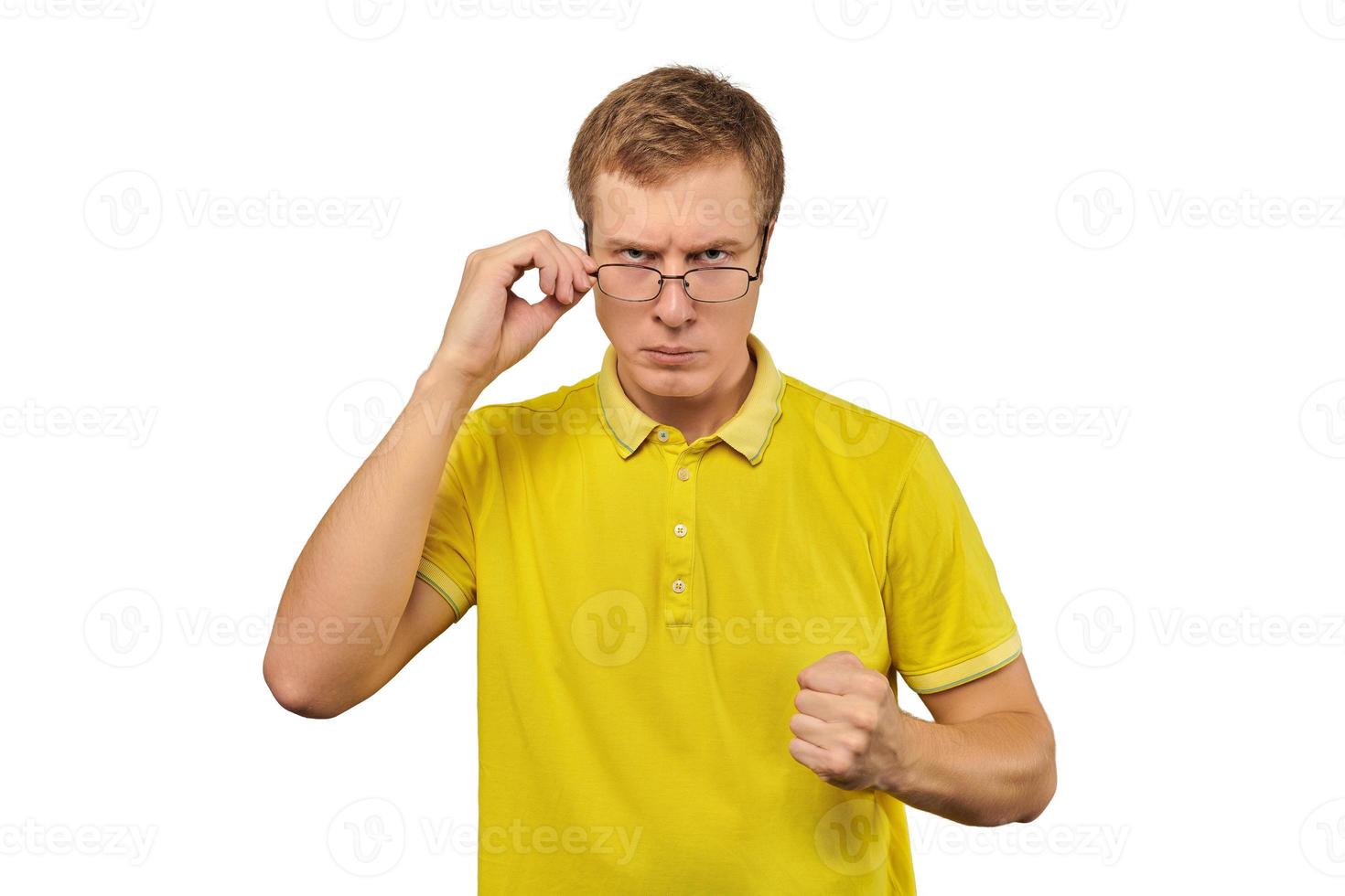 Unhappy geek guy in glasses and yellow T-shirt ready to fight with fists isolated white background photo