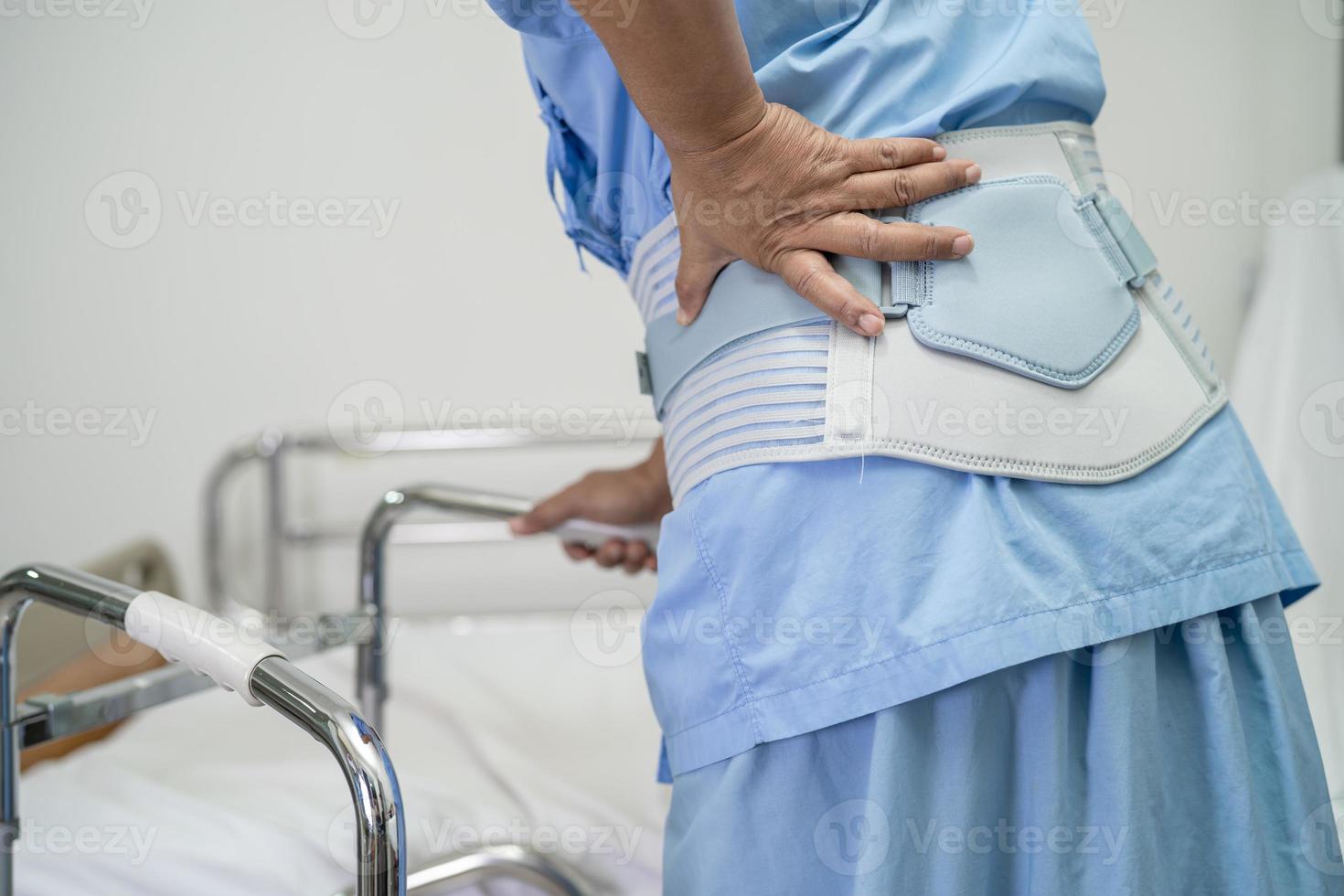 Asian lady patient wearing back pain support belt for orthopedic lumbar with walker. photo