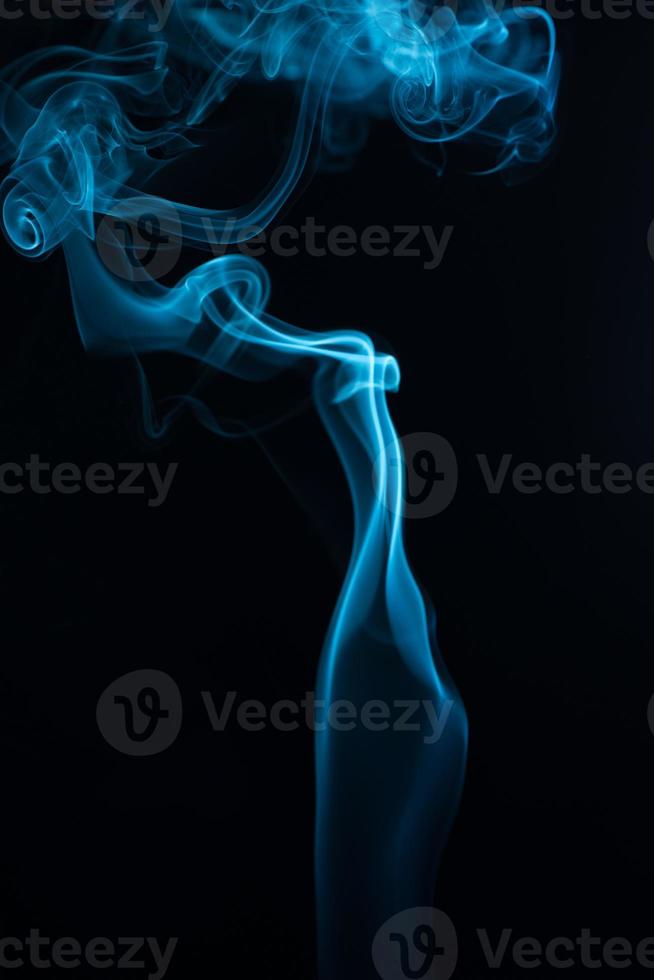 un disparo vertical de humo de tabaco azul sobre un fondo negro foto