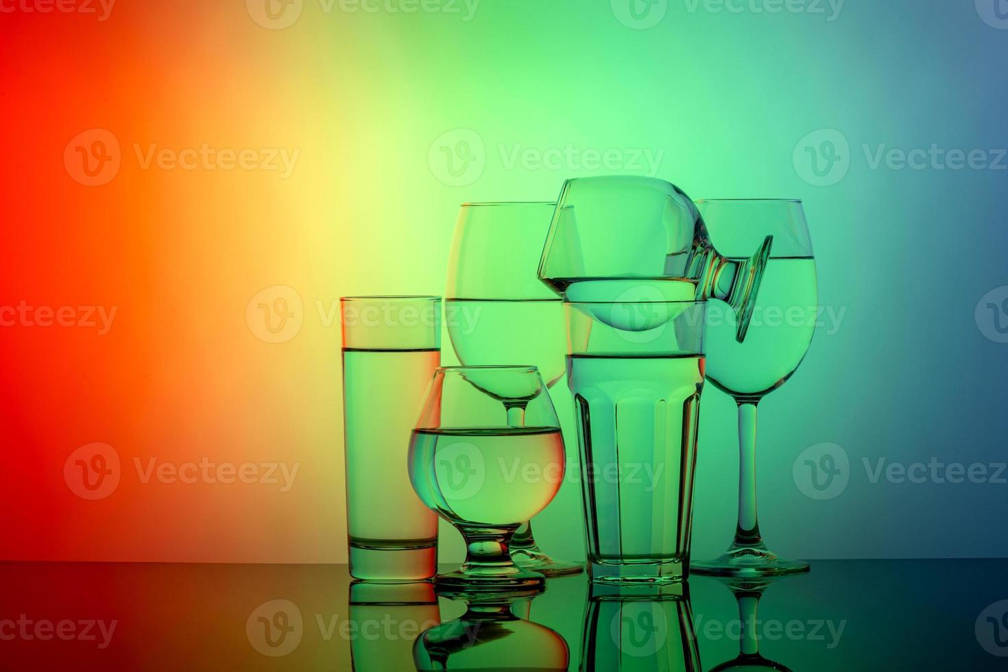 Some glasses for different drinks stacked on a colorful background photo