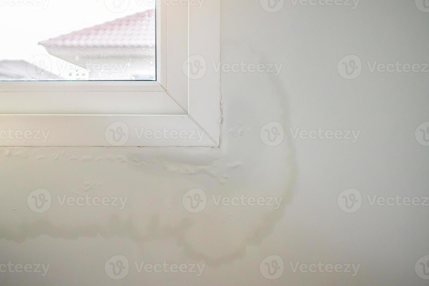 La pared de la casa cerca de la ventana con una mancha de agua muestra pintura desconchada foto