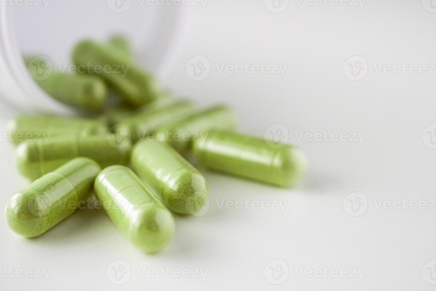 Herbal medicine capsules with bottle on white background photo