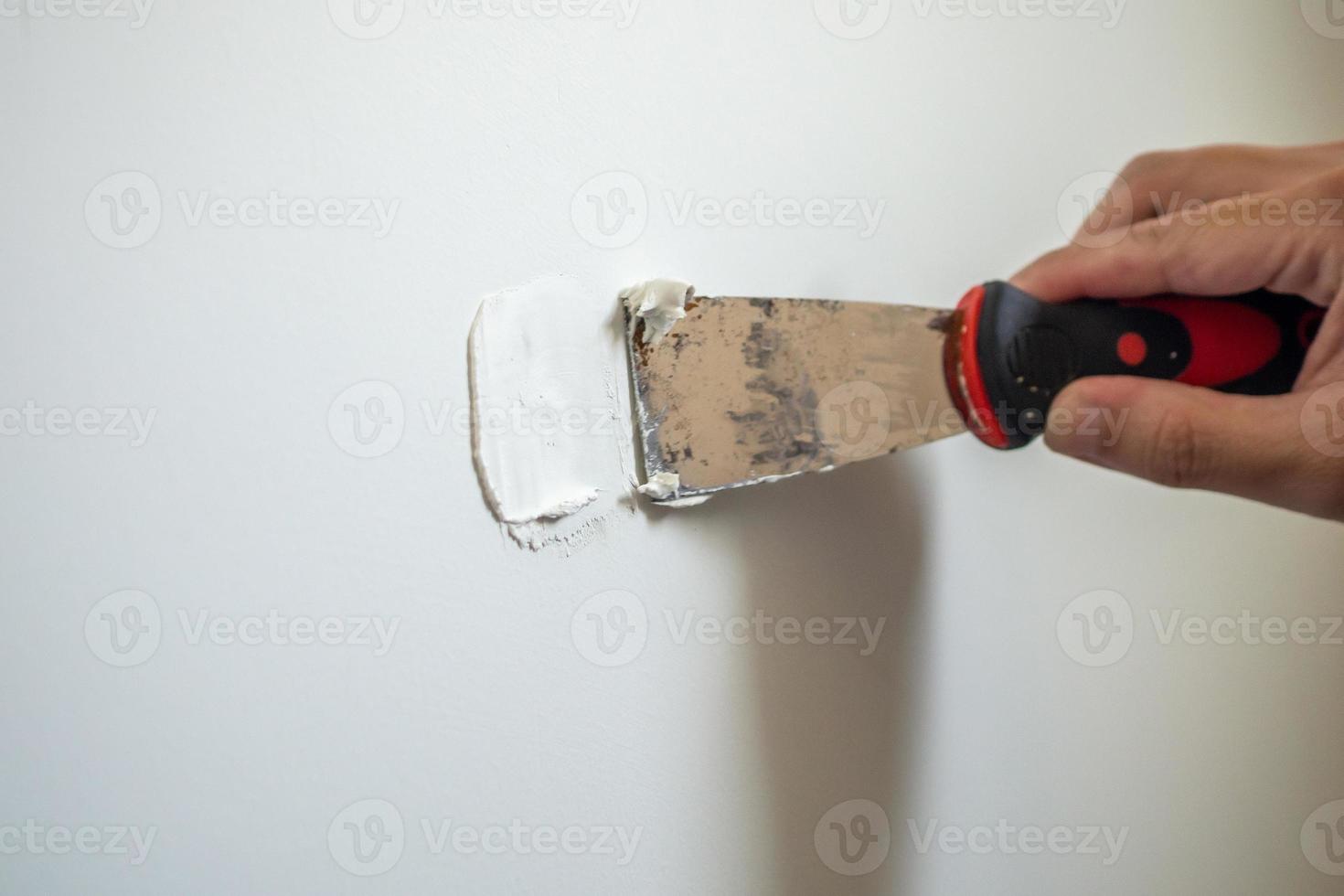 Man repairing crack white wall with spatula photo