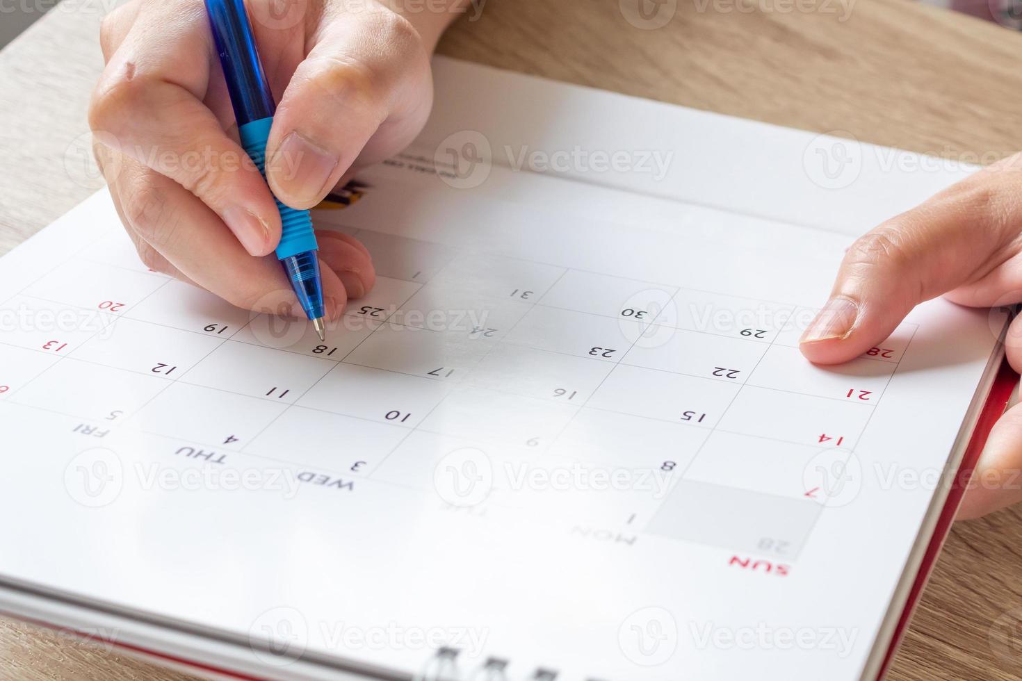 Woman hand with pen writing on calendar date business planning appointment meeting concept photo