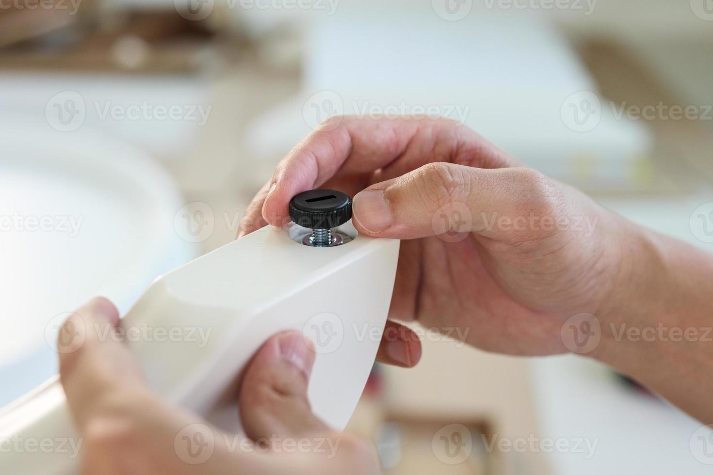 Asian man assembling furniture at home with adjustable table leg photo