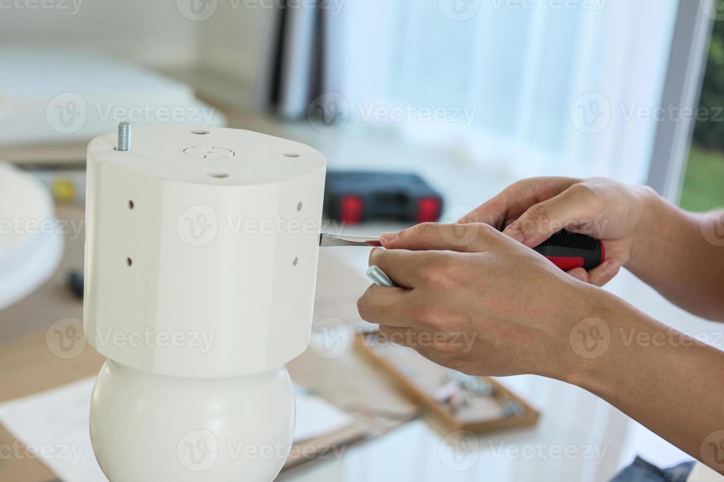 Asian man assembling white table furniture at home photo