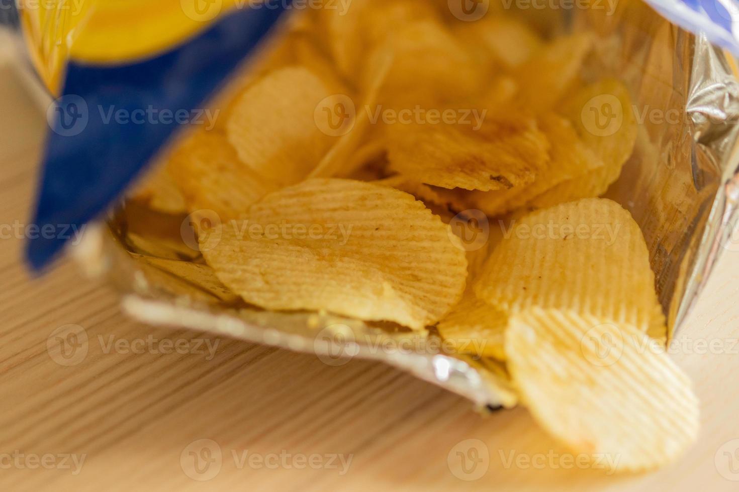 crispy potato chips in snack bag on wood table photo