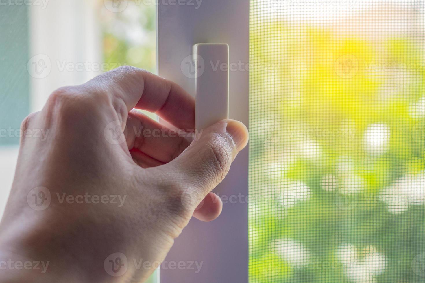 Hand hold mosquito net wire screen handle on house window photo