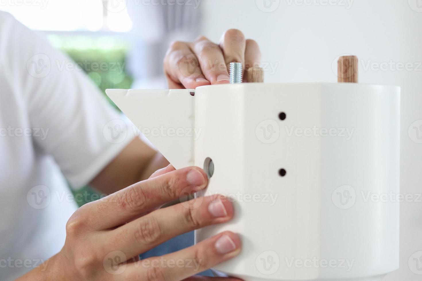 Asian man assembling white table furniture at home photo